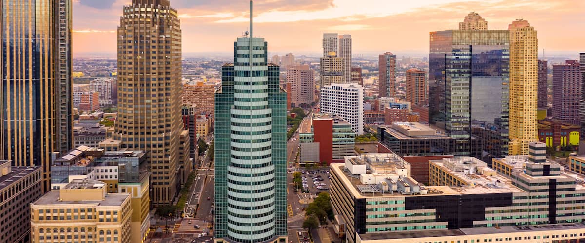 A cityscape with tall buildings, including a distinctive cylindrical skyscraper and a building with a unique tiered top.