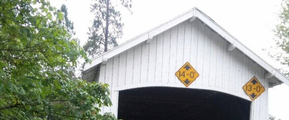 A covered bridge with a weight limit sign of 14-0 tons and a 13-0 tons sign.