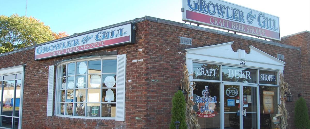 A brick building with a sign reading "Growler & Gill Craft Beer Shoppe".
