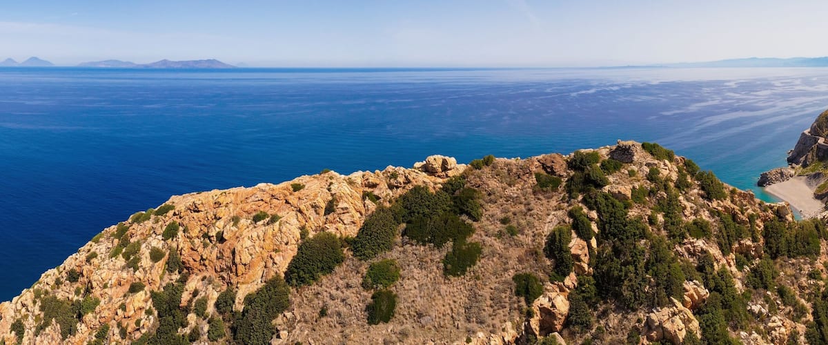 A rugged coastline with rocky cliffs and a clear view of the ocean.