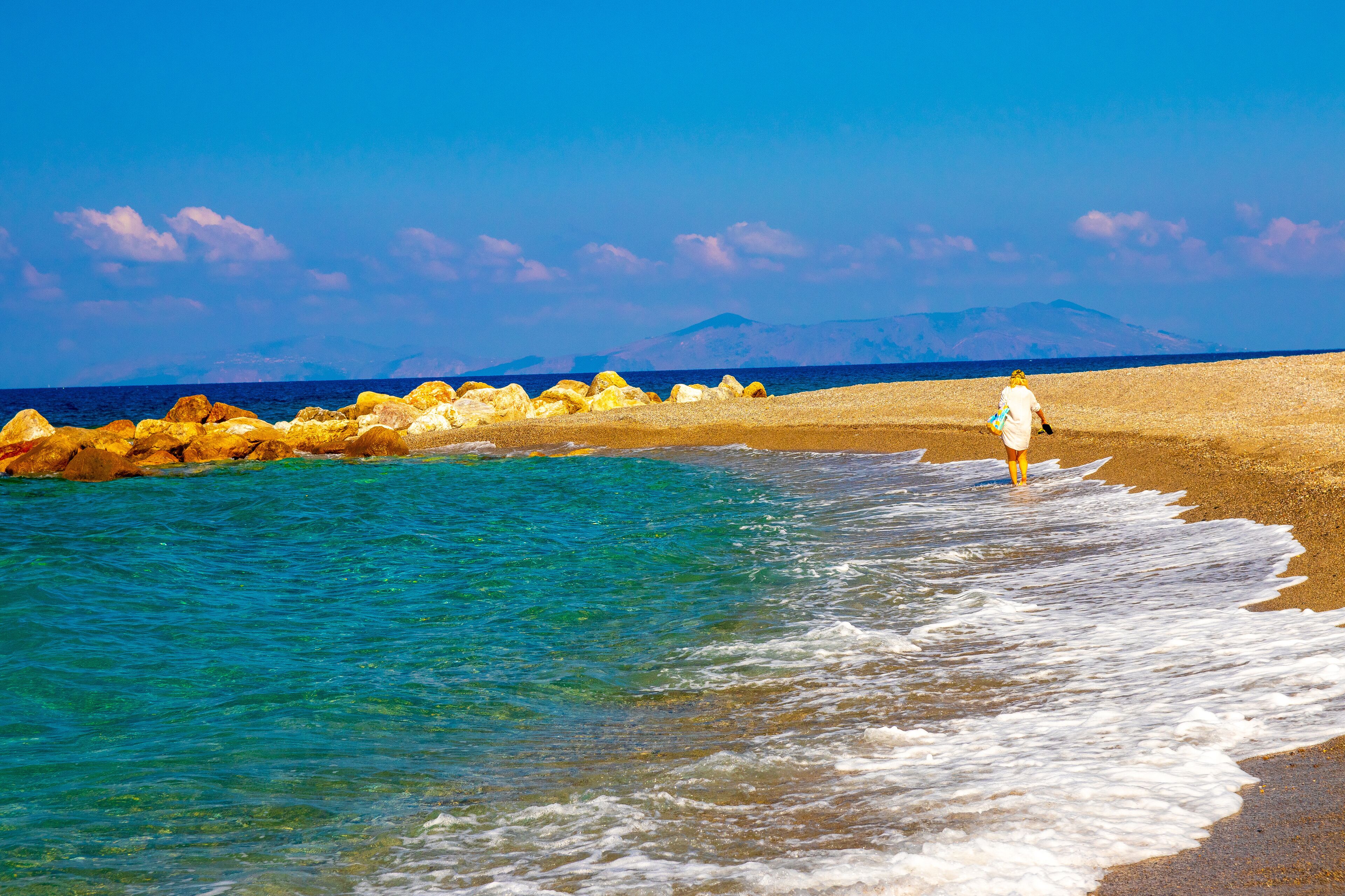 Gioiosa Marea, Sicily, Italy – 01 Oct 2023. Woman walking on the rocky Tyrrhenian coast in the bay of Gioiosa Marea (province of Messina) in Sicily, Italy.