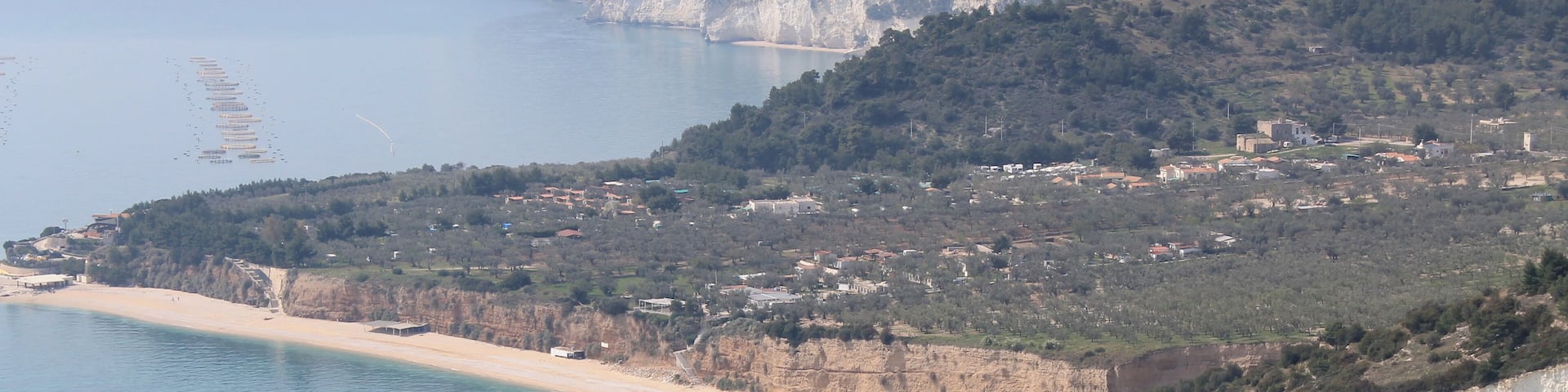 A coastal landscape with a sandy beach, cliffs, and a town in the background.