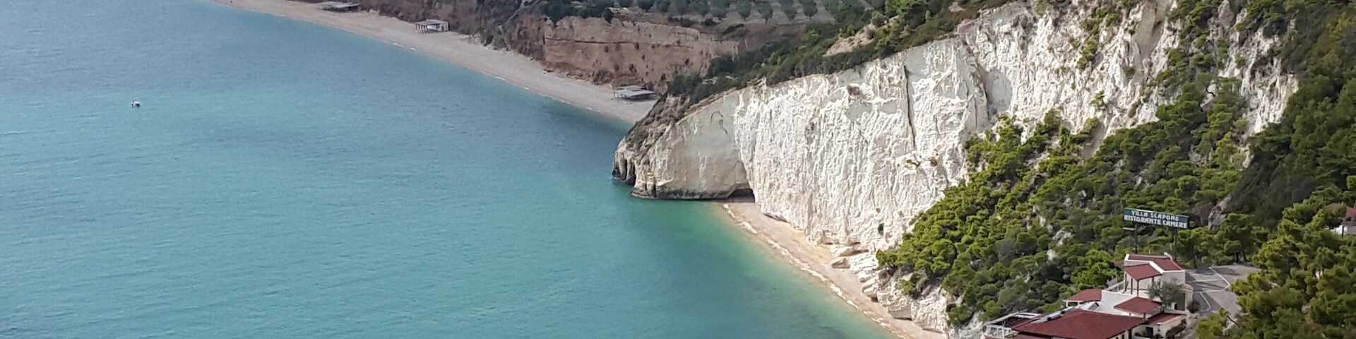Un paisaje costero con una playa, acantilados y edificios.