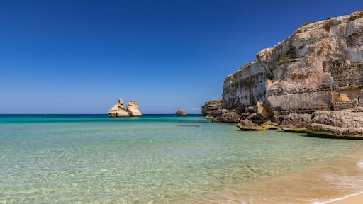 The bay of Torre dell'Orso, with its high cliffs, in Salento, Puglia, Italy. Turquoise sea and blue sky, sunny day in summer. A beach of fine white and pink sand. The stacks called the Two Sisters.