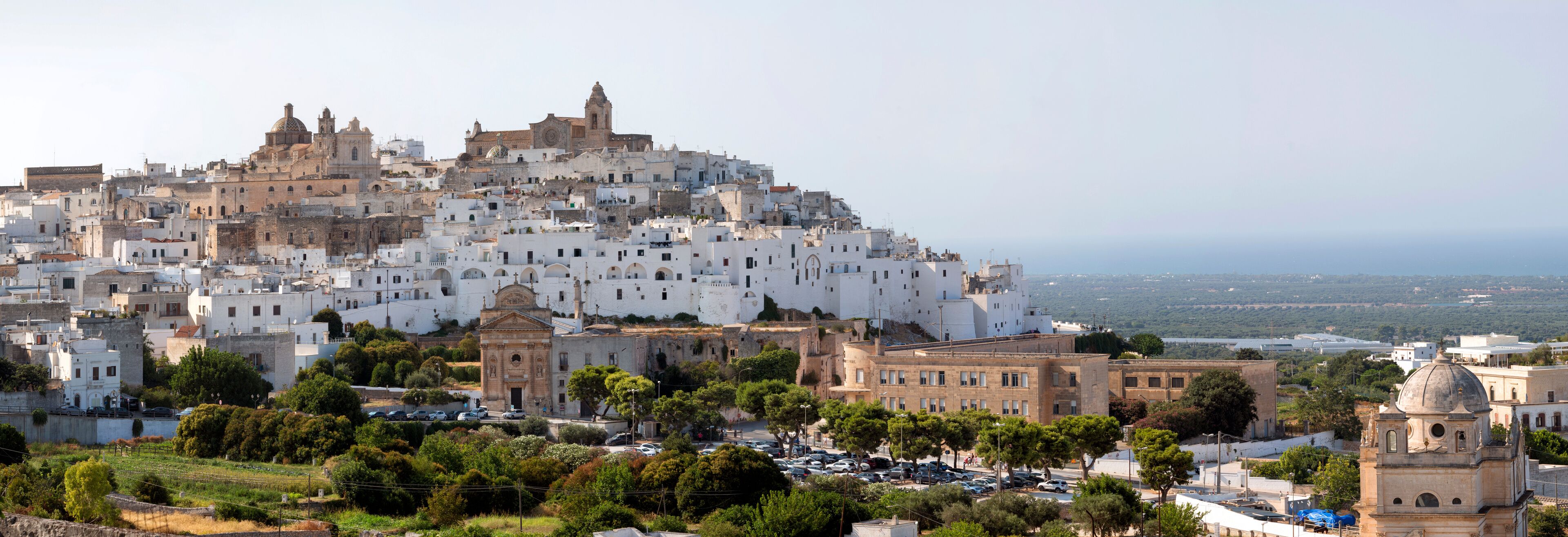 A coastal cityscape with white buildings, a prominent church, and a view of the sea.