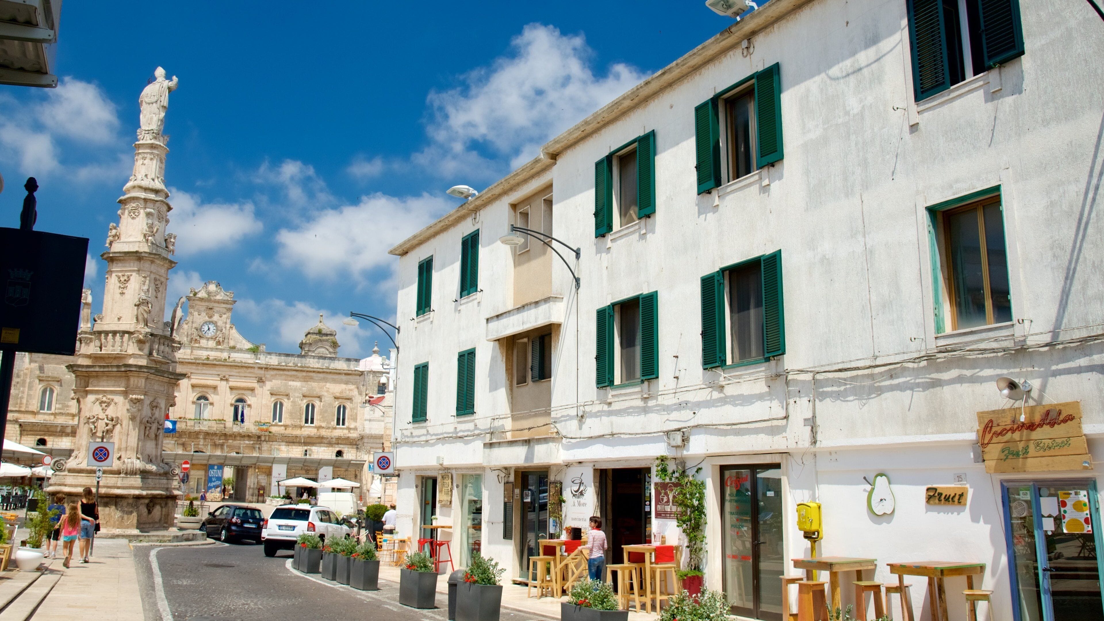 A street with a statue, buildings, and outdoor seating.