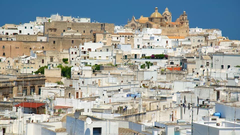 A densely packed urban landscape with white buildings, a prominent church with a golden dome, and a clear blue sky.