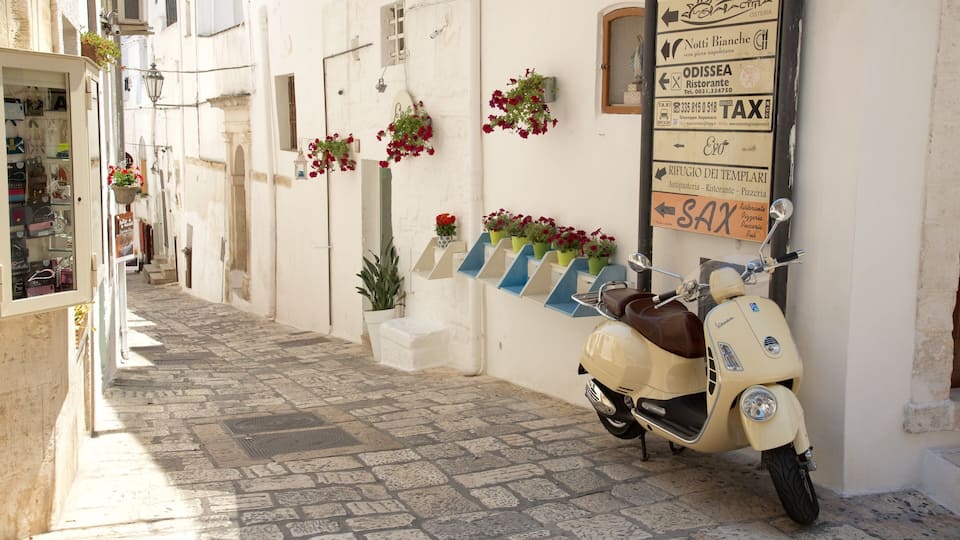 A narrow cobblestone street with a vintage scooter parked on the right.
