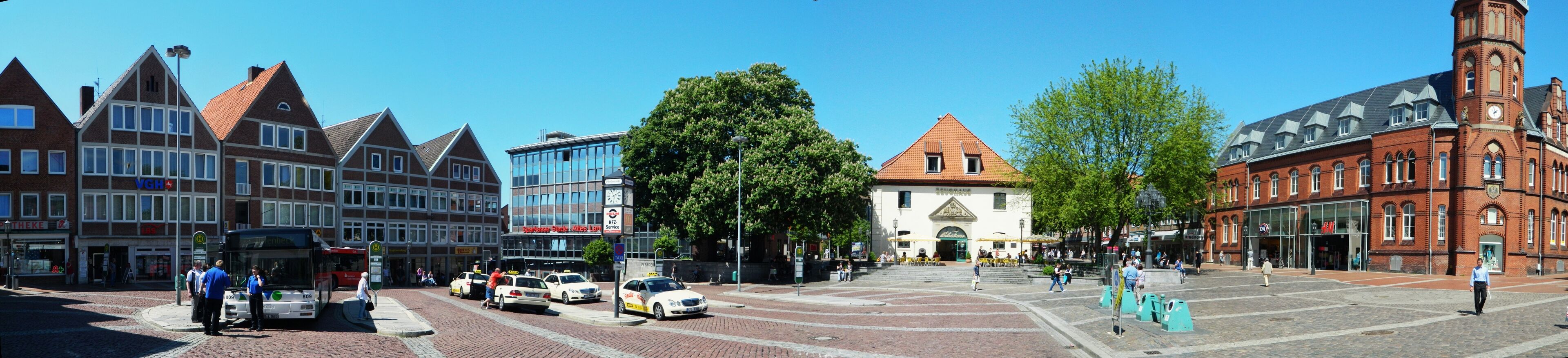 A historic town square with traditional buildings, a clock tower, and a modern glass building.