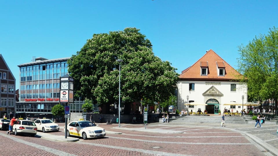 A historic town square with traditional buildings, a clock tower, and a modern glass building.