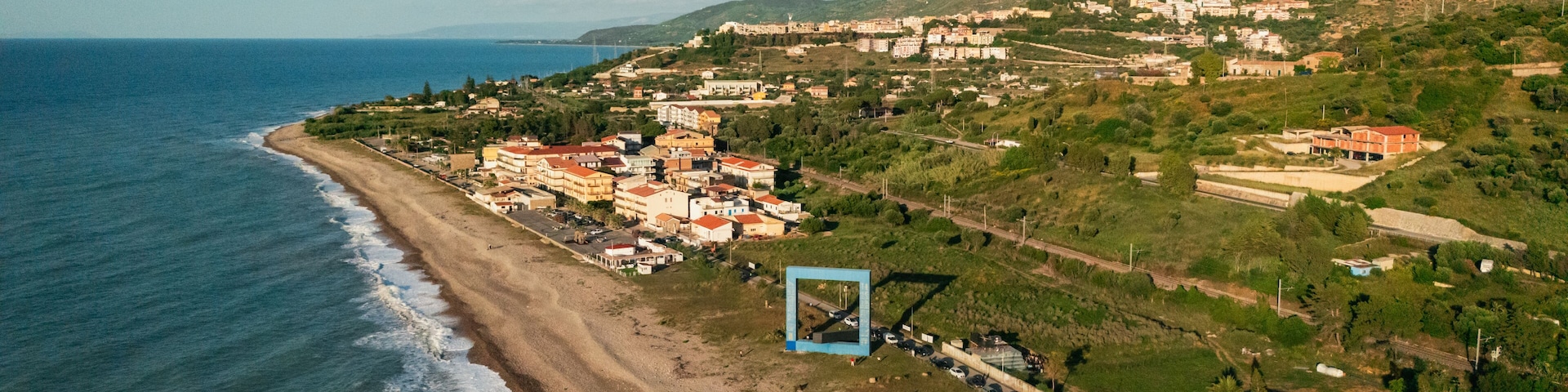Un pueblo costero con playa, edificios y un paisaje montañoso.