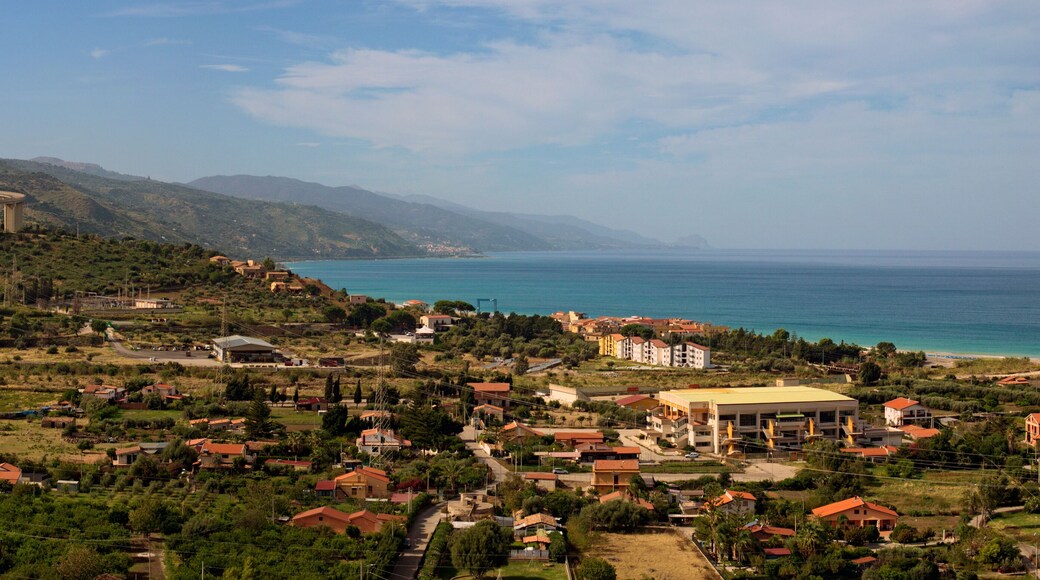 Picturesque panoramic landscape view of Sicily at sunny day. Curved automobile viaduct in mountains near Santo Stefano di Camastra. Small houses near the sea. Travel and tourism concept. Sicily, Italy