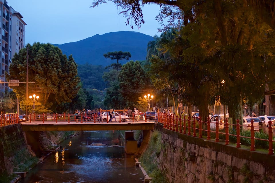 A river with a bridge, trees, and buildings in the background.