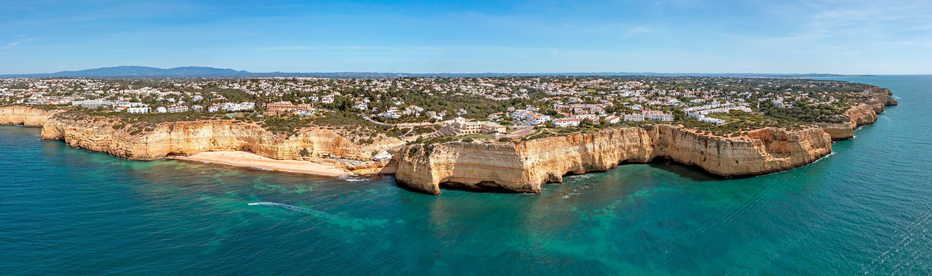 A coastal town with a prominent cliff and clear turquoise waters.