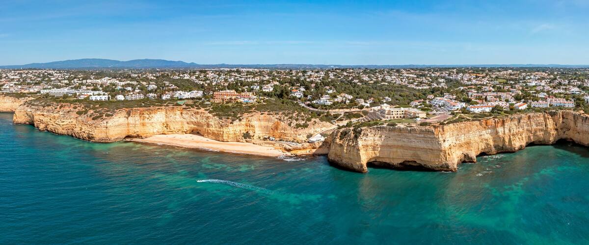 A coastal town with a prominent cliff and clear turquoise waters.