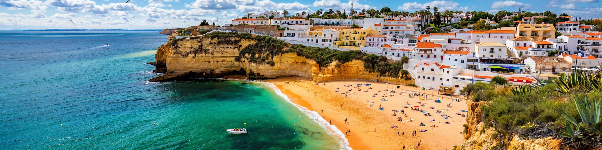 A coastal town with a beach, cliffs, and colorful buildings.