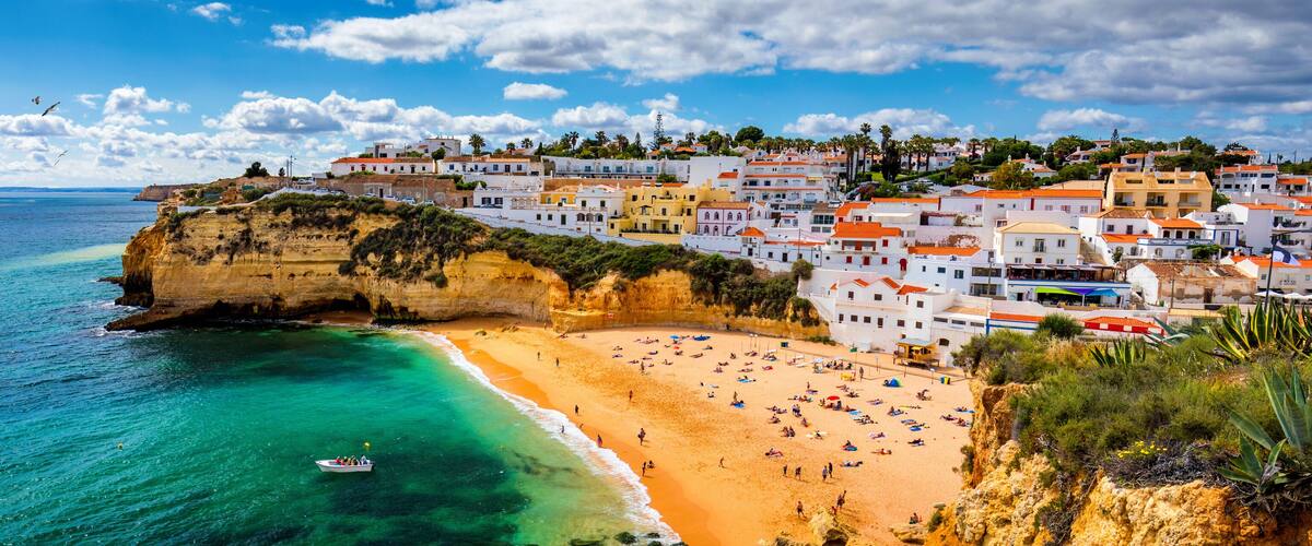 A coastal town with a beach, cliffs, and colorful buildings.