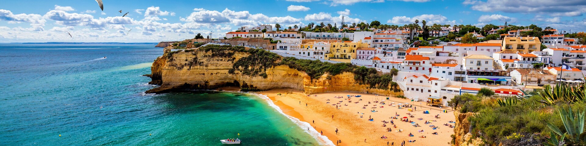 A coastal town with a beach, cliffs, and colorful buildings.