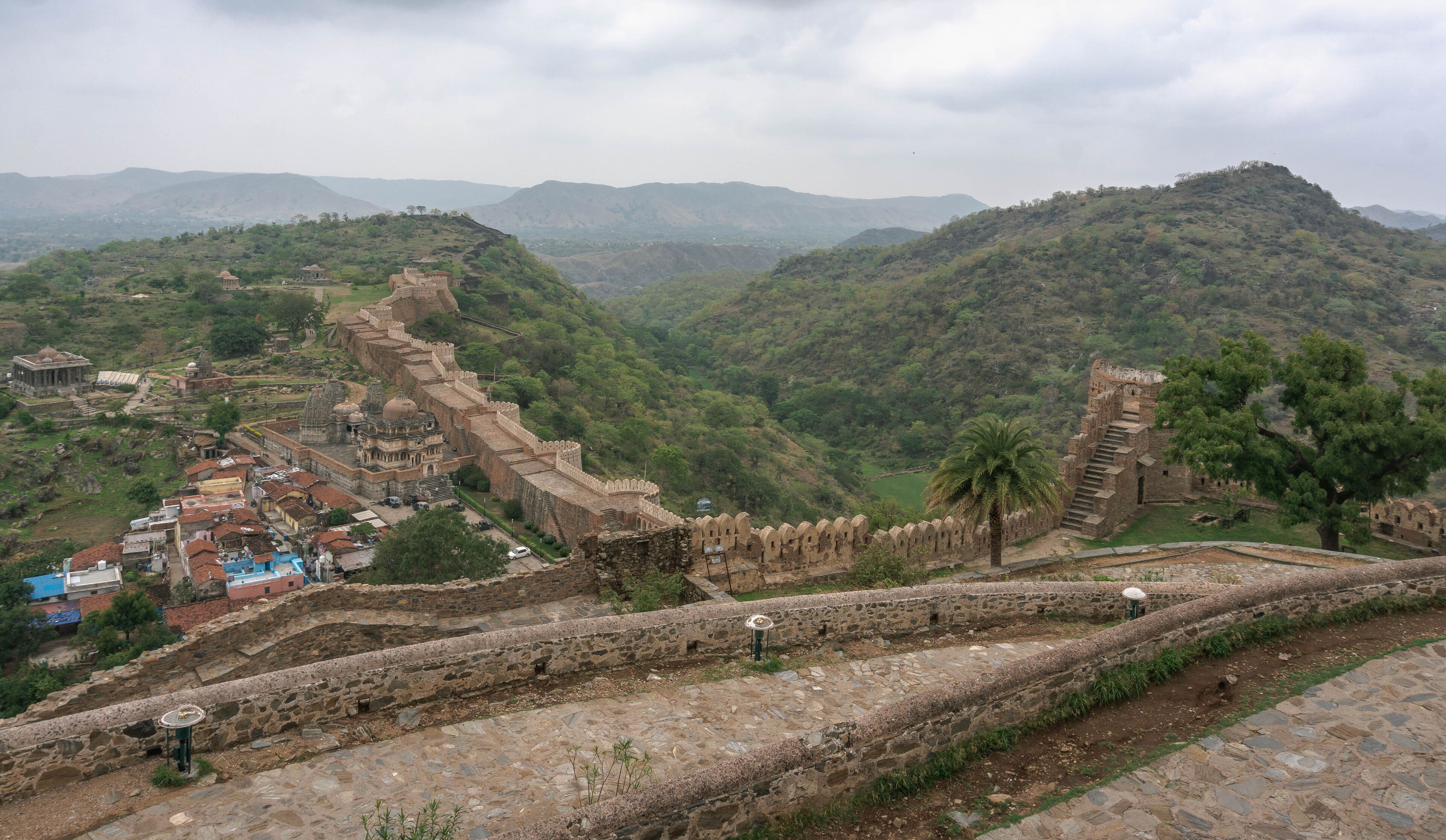 A historic fort with a long wall, a small temple, and a village in the valley below.