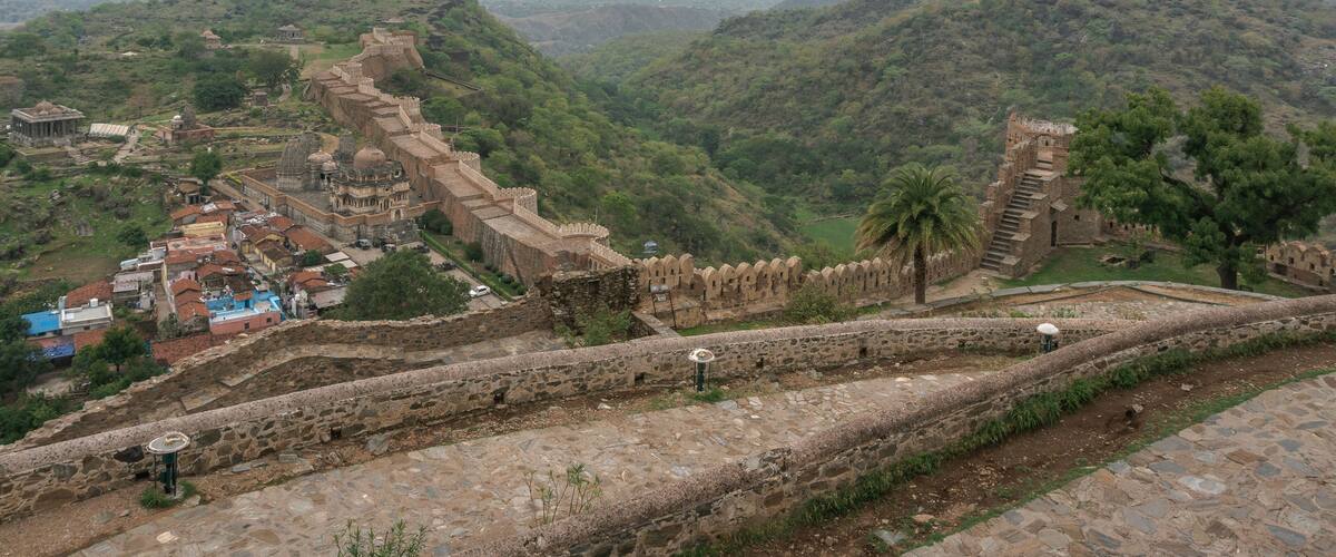 A historic fort with a long wall, a small temple, and a village in the valley below.
