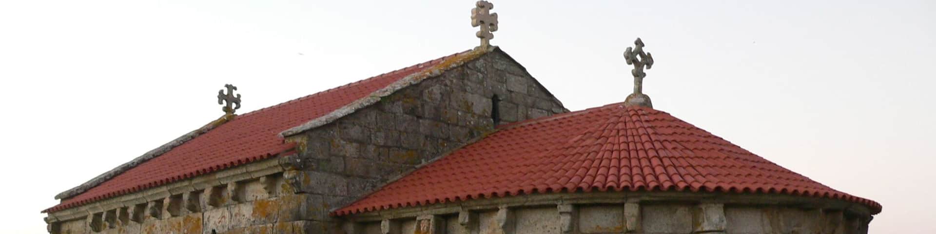 A stone building with a red-tiled roof and two crosses on top.