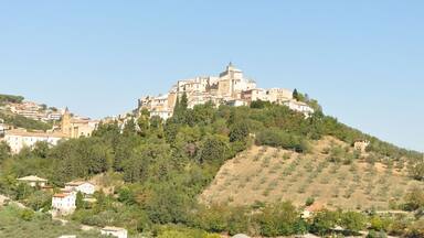 A hilltop town with historic buildings, a prominent church, and lush greenery.