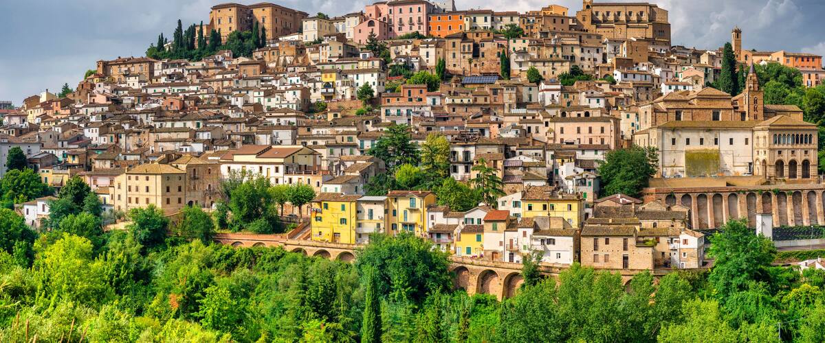 A densely packed hillside town with historic buildings, a prominent church, and a clock tower.