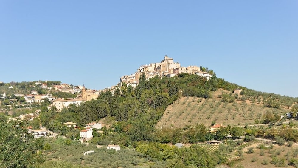 A hilltop town with a prominent church and surrounding greenery.