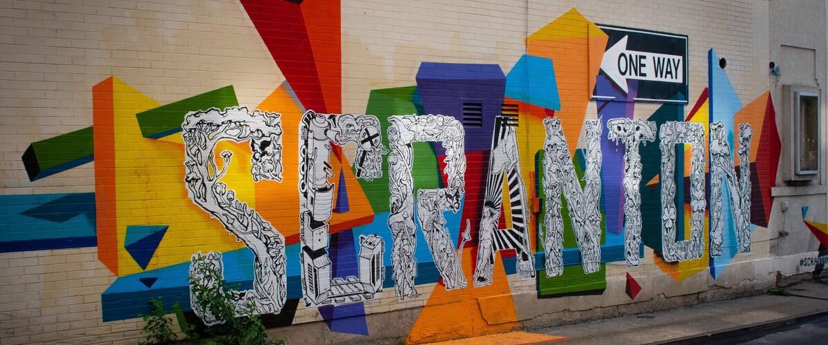 Un mural colorido con formas geométricas y la palabra "SECRETION" en una pared de ladrillo.