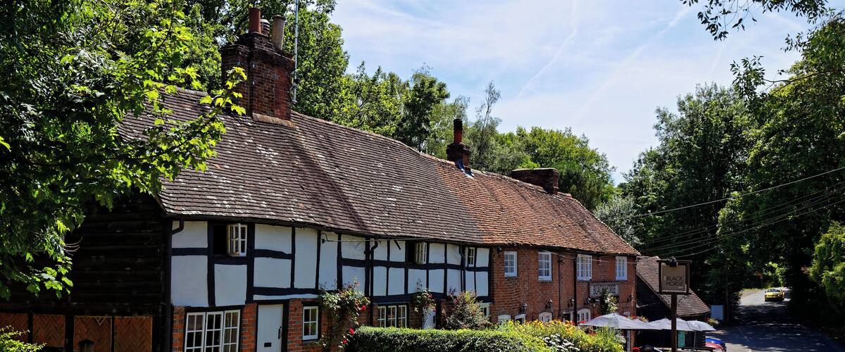 The Black Horse Inn public house on Nuthurst Street in Nuthurst, West Sussex, England. The Black Horse Inn, reputedly haunted by a local murderer who drank here, is part of the 17th-century Black Horse Cottages Grade II listed buildings. Camera: Canon EOS 6D with Canon EF 24-105mm F4L IS USM lens. Software: RAW file lens-corrected and optimized with DxO OpticsPro 11 Elite and Viewpoint 2, and further optimized with Adobe Photoshop CS2.