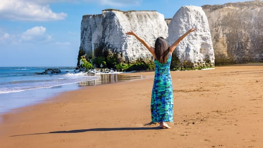 A happy woman enjoys the view of the beautiful beach of Botany Bay in Kent, England, with white cliffs and sunshine