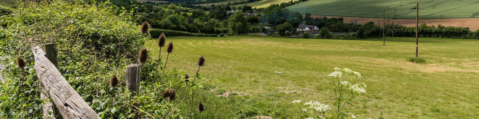 Sunny morning, view of a village and hills with fields, blue sky and white clouds