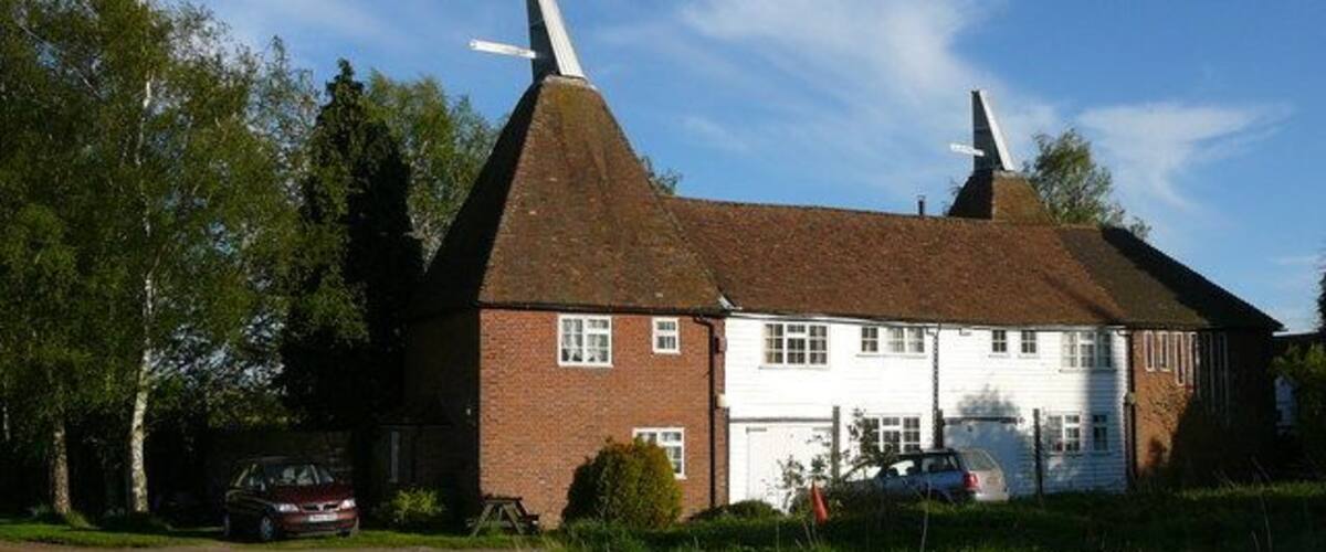 A traditional house with a thatched roof, a white garage, and a red car parked in front.