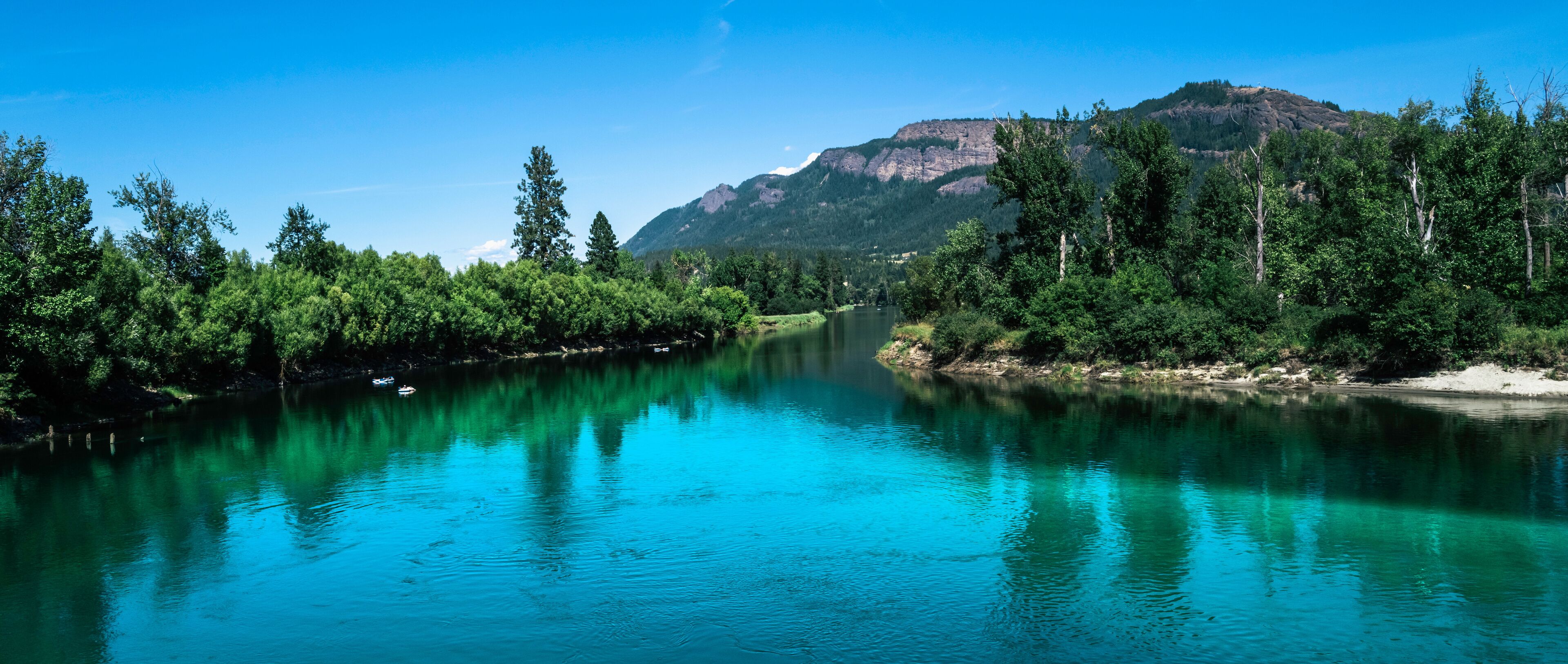Tranquil landscape of the turquoise-colored river water and green forest at Fortune Creek park in Enderby, British Columbia, Canada