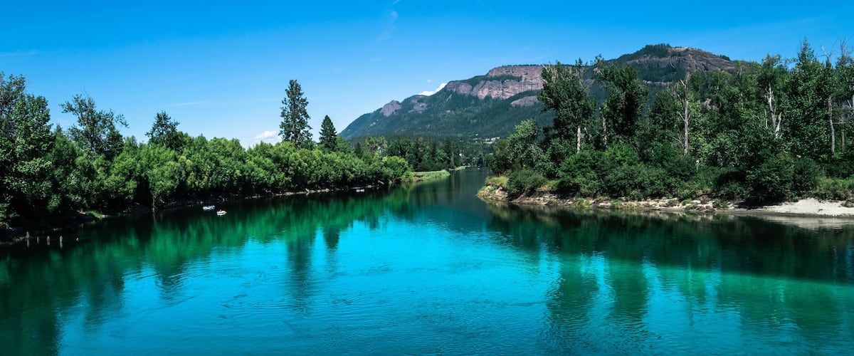 Tranquil landscape of the turquoise-colored river water and green forest at Fortune Creek park in Enderby, British Columbia, Canada