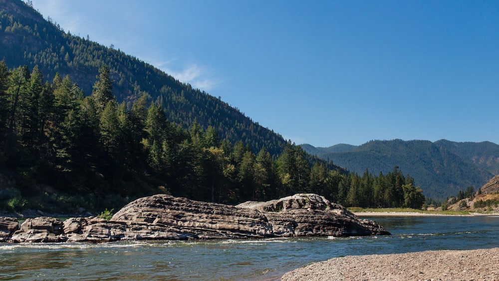 Beautiful landscape with mountains and mountain river with stone banks on a summer sunny day with clear blue sky. Panorama. Alberton, MT, USA