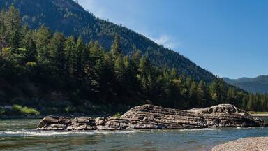 Beautiful landscape with mountains and mountain river with stone banks on a summer sunny day with clear blue sky. Panorama. Alberton, MT, USA