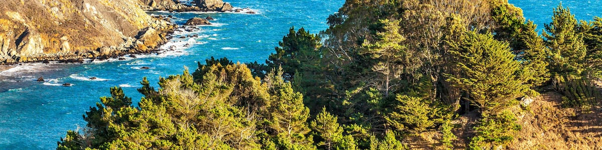 California scenic coastal cliffs along the Pacific Ocean with the city of San Francisco in the background. Blue sky with drifting clouds
