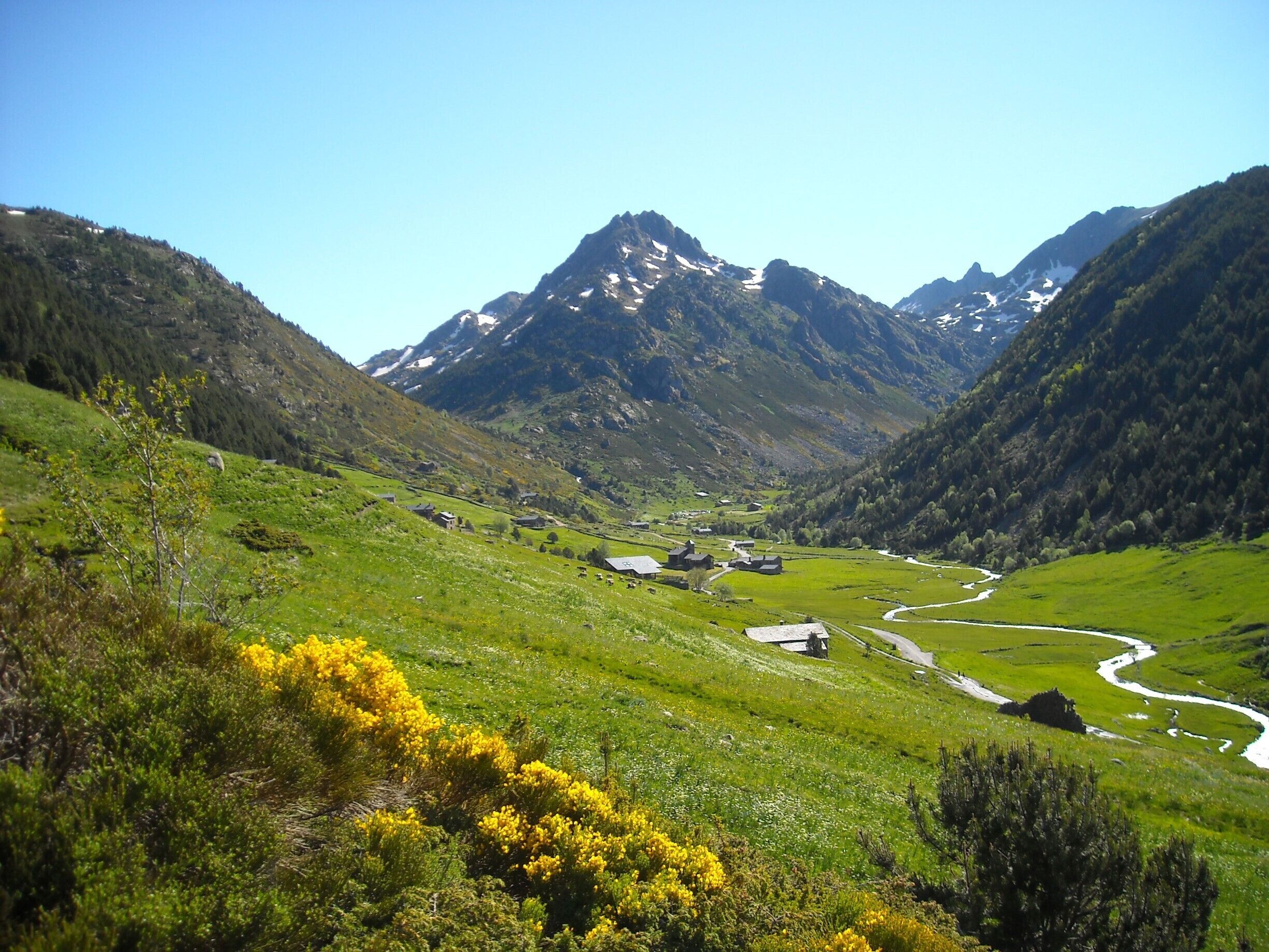 A valley with a river, green hills, and a mountain range.