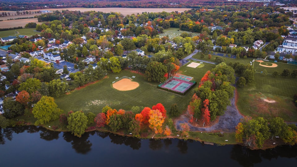 An aerial view of a residential area with houses, a baseball field, and a lake.
