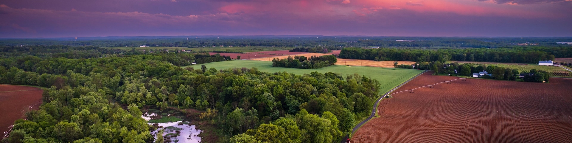 A rural landscape with a river, fields, and a farmhouse.