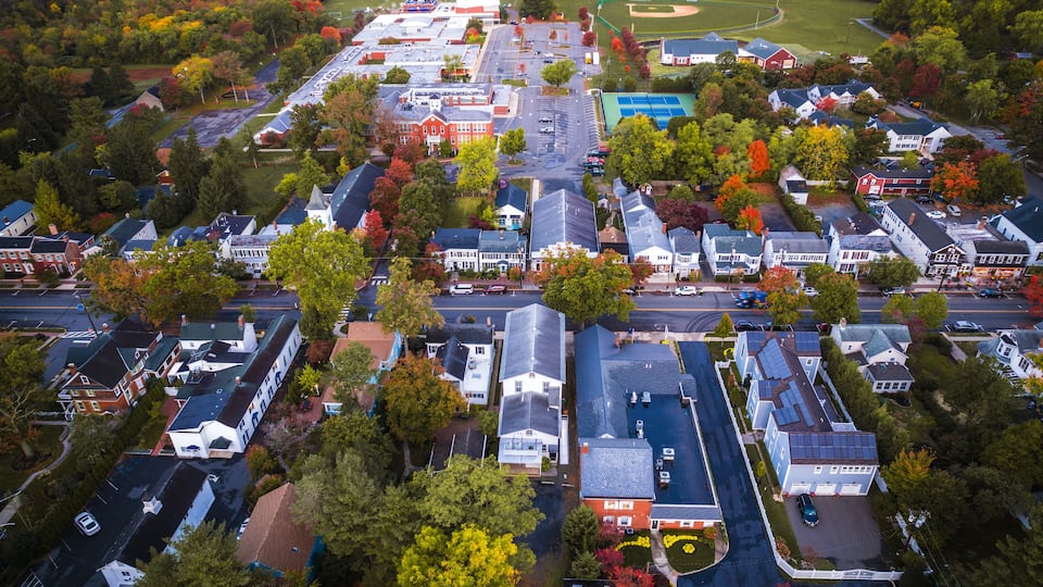 An aerial view of a residential area with houses, a school, and a sports field.