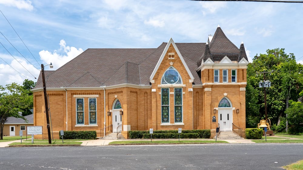 A brick building with a large arched window and a bell tower.