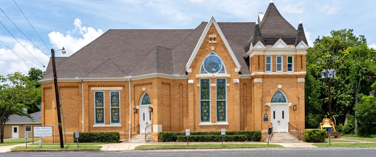 A brick building with a large arched window and a bell tower.