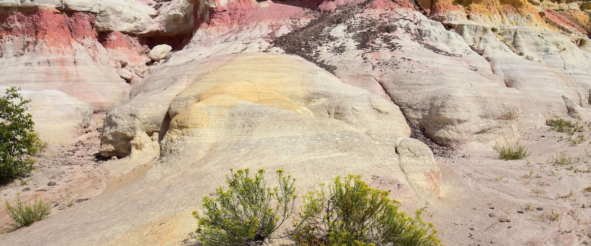 A colorful rock formation with distinct layers of pink, yellow, and white.