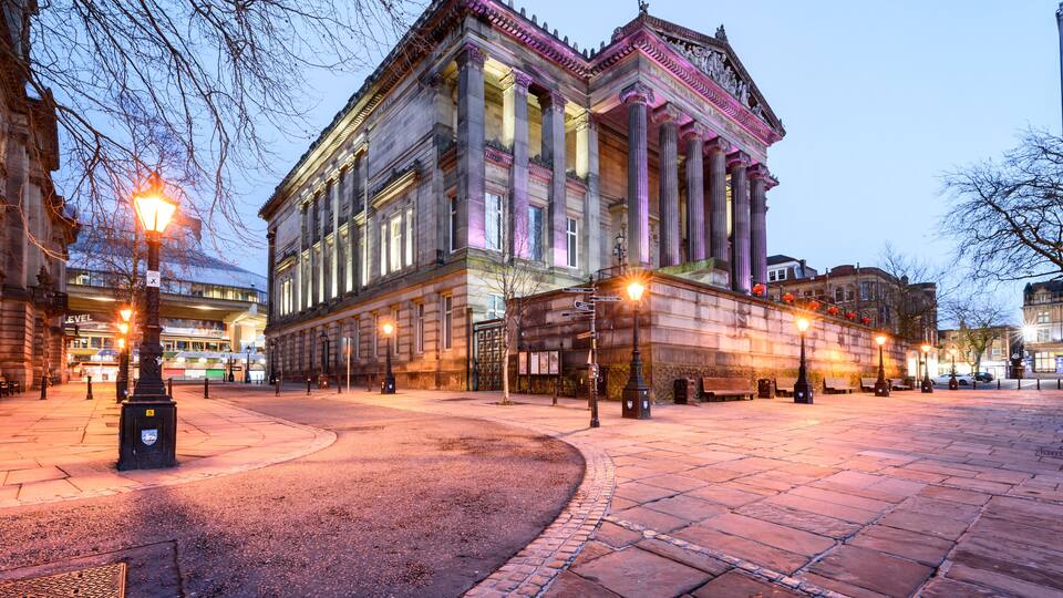 A historic building with large columns and a classical facade, illuminated by street lamps.