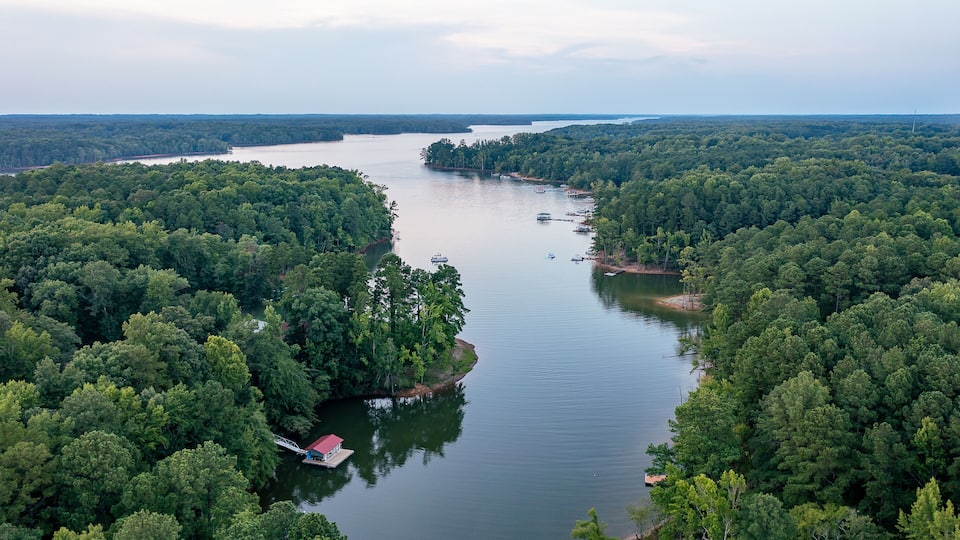 A river winding through a densely forested area with boats and a small dock.