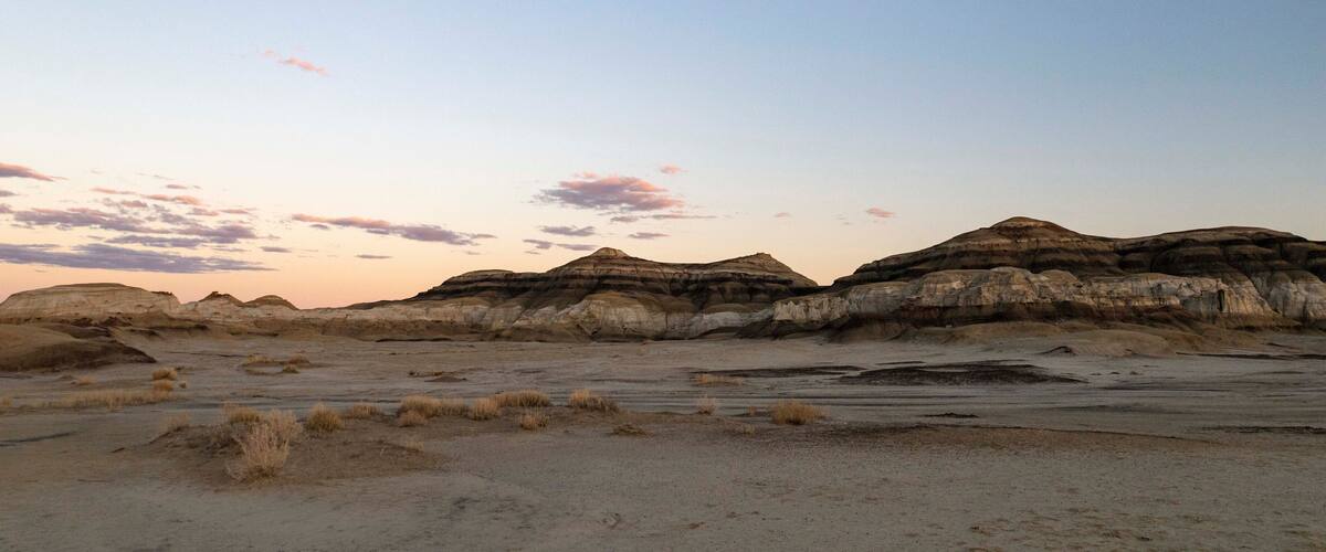 A desert landscape with eroded rock formations and sparse vegetation.