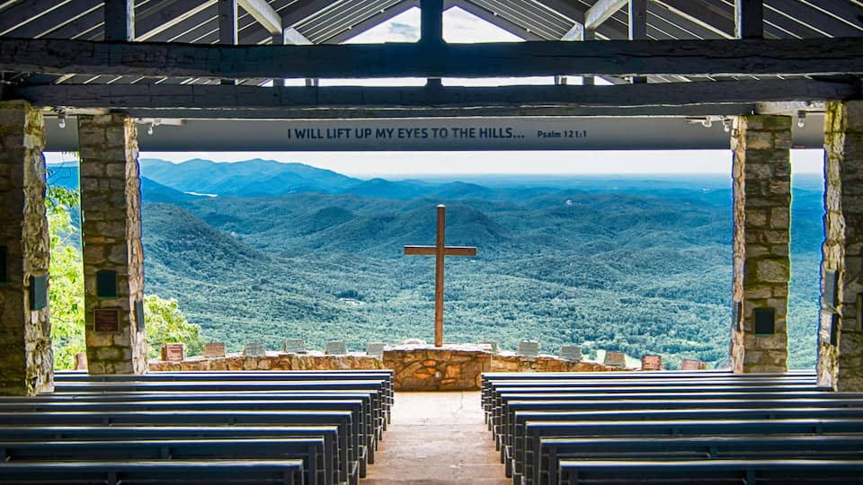 A church with a cross and a view of a mountainous landscape.