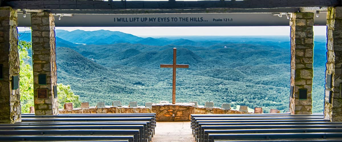 A church with a cross and a view of a mountainous landscape.